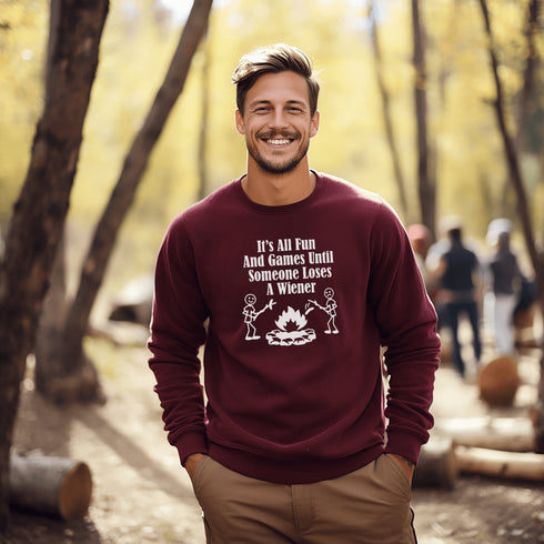 Our Camping sweatshirt features two stick people roasting wieners over a campfire with the hilarious saying, "It's All Fun & Games Until Someone Loses A Wiener."